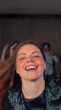 Çekici seksi kızıl uzun saçlı kadın arkadaşlarının önünde dans ediyor. Süper yavaş çekim ve gerçek zamanlı dans. Tipik doğum günü eğlencesi Dikey çekim.