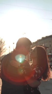 Çekici erkek ve genç bayan şehirde eğleniyor. Duygusal olarak dans ediyorlar, gülüyorlar ve gülüyorlar. Sun lightleak. Orta görüş. Dikey çekim.