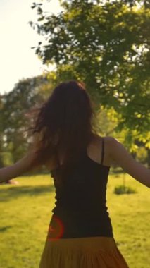 Genç ve çekici bir kadın parkta mutlulukla koşuyor. Etrafında dönen ağaçlara dokunup gülümsüyor. Orta atış. Çok kaygısız görünüyor. Süper yavaş çekim dikey çekim.