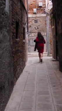 Dikkatsiz kadın turistin, elinde şapkasıyla Venedik 'in bahçesinde koşup İtalyan bayramlarının tadını çıkarması yaz rüzgârları esiyor. Avrupa 'da hafta sonu. Geniş açı. Dikey çekim.