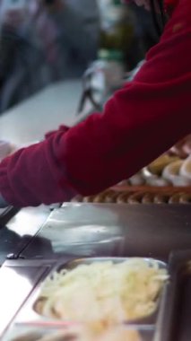 Sosisli sandviç küçük market ayrıntıları. Satıcının ve müşterinin elleri. Sosis ve ekmek dikey çekim.