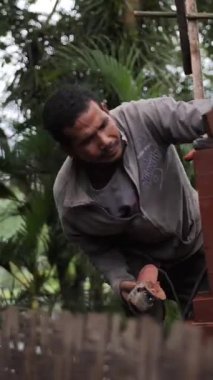 BALI, İNDONEZYA - 20 Mart 2018: Bali adasının caddesinde çalışan Endonezyalı. Yuvarlak testereyle dikey çekim yapıyor..