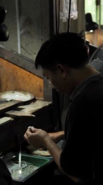 BALI, INDONESIA - 20 Mart 2018 Bali adasındaki kuyumcu şehri, Asyalılar altın, gümüş, elmas ve değerli metallerden oluşan bir fabrikada pahalı mücevherler topluyor. Dikey çekim.
