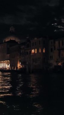 Venedik 'in gece mimarisi Merkez Kanal' dan görüntüsü. Tarihi binaların yakınında ay ışığı ve su yansımaları. Dikey çekim.