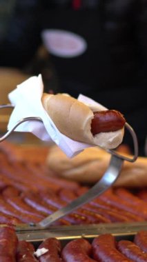 Sosisli sandviç küçük market ayrıntıları. Satıcının ve müşterinin elleri. Sosis ve ekmek dikey çekim.