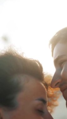 4k ultrahd selfie, balayı tatilinde tropikal adada altın gün batımında öpüşen mutlu genç çifti çekti. Bokeh Sahili ve Deniz Okyanusu 'nda bulanık. Dikey çekim.