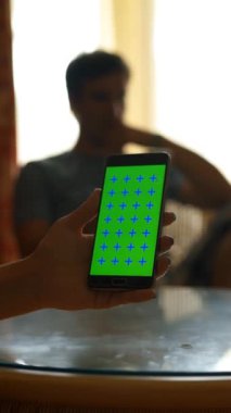 İnternette el ele gezinen mobil bir cihaz tablet bilgisayarında oyun oynayan bir adamla arka plandaki otel odasını bulanıklaştırdı. 4k uhd üçayak dikey çekim.