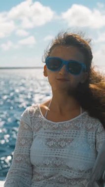 4k Uhd. Güzel genç mavi şaşırtıcı Karayip Denizi yata kenarında oturan güneş gözlüğü güzel kız. Saona Adası. yeşil ve turuncu tarzı. Mutluluk gülümse. Brownhair. Güneşli,