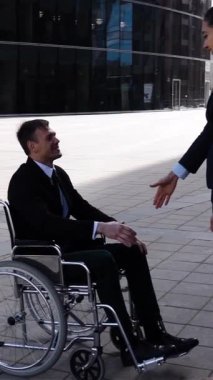 Resmi takım elbiseli genç çekici bir iş kadını gün batımında engelli meslektaşıyla el sıkışıyor. Süper yavaş çekim. Geniş açı. 480 fps. Dikey çekim.