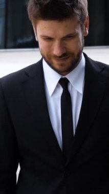 Gülümseyen Mutlu Kafkas İş Adamı Şehir Arkaplanı - Arkaplandaki modern şehir gökdelenlerine karşı tutkulu genç Kafkasyalı iş adamı portresi yavaş çekimde yakın çekim. Dikey çekim.