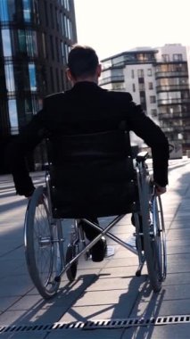 Arkadan görünüşü wheelchai bir geçersiz sakat işadamı bg iş fırsatları için mimari camlar ile. Süper ağır çekim sessiz onun sandalyede hareket. Kamera geri onunla git sorunsuz. Geniş görüş