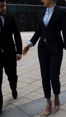 İş arkadaşları, iş adamları ve takım elbiseli iş kadınları yürürken tokalaşıyorlar. Ağır çekim geniş çekim. 300 fp. Modern ofis geçmişi. Teal ve turuncu renk. Dikey