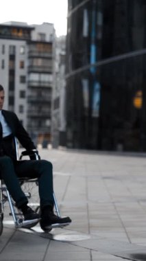 Tekerlekli sandalyede yuvarlanan ve morali bozuk yakışıklı bir adam. 4k UHD 'lik bir portre. Açık deniz mavisi ve turuncu iş alanı yakınında. Başarısızlık konsepti. Dikey çekim.