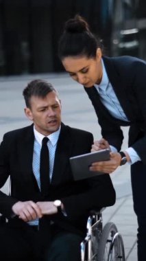 Geçersiz sakat patron iş adamı başarılı ve güçlü tekerlekli sandalyede takım elbiseli ve bayan sekreteri dışarıda dijital ped ya da tabletle çalışıyor. Dikey çekim.
