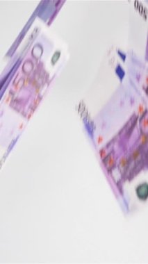Ağır çekim. Havada çok az Avro banknotu uçar ve beyaz yüzeye dikey çekim yapar..