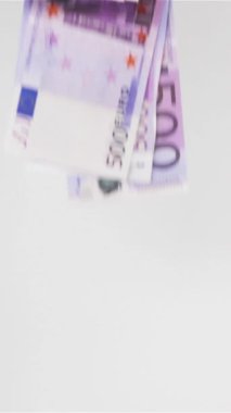 Ağır çekim. Havada çok az Euro uçar ve beyaz yüzeyde dikey çekim yapar..