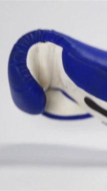 Ağır çekim. Klasik koyu mavi kutu eldivenleri düşüp beyaz yüzeyde zıplar. Dövüş konseptine karşı Adversary 'e meydan oku. Dikey Çekim.