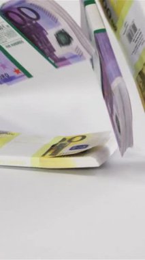 Yavaş çekimde birkaç Avro para destesi beyaz yüzeyde zıplıyor. 500 ve 200 banknot Dikey Vuruş.