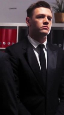 Üç özgüvenli yakışıklı iş adamının havalı destansı çekimi. Ofis içeride. Kafalarını kameraya çeviriyorlar. Süper yavaş çekim dikey çekim.