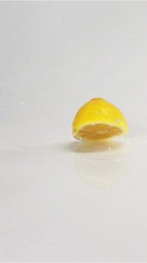 Birkaç taze sarı lezzetli dilimlenmiş limon yere düşüp ıslak beyaz yüzey üzerinde atlamak. Yüksek-hizli-kamera ile slowmotion modunda vurdu. Limon çok hızlı izole kamera beyaz cyclorama arka plana hareket