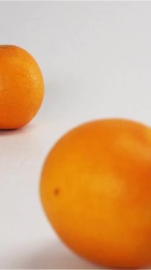 Az sayıda lezzetli ıslak portakal yavaş çekimde beyaz kuru yüzeye düşüp zıplıyor. Meyveler kameradan yüksek hızda hareket ediyor. Hızlı hayalet dikey çekim esnemesi.