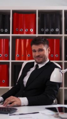 4k ultrahd. Young attractive successful businessman showing you fuck sign with funny smile, third finger inside office with table, computer, digital pad Vertical Shot.