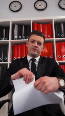 Ofis koltuğunda oturan kızgın yakışıklı işadamı bir belgeyi, sözleşmeyi ya da anlaşmayı yırtıp atıyor. Kağıt parçaları. Şirket konseptiyle doktorları yok etmek. Dikey Çekim.