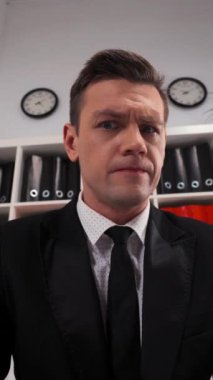 Genç yakışıklı iş adamı büyüteç merceğine bakar ve sende ilginç bir şeyler bulur. Geniş açı. Görüntüyü doğrudan kameraya yansıtıyor ve daha da büyüyor. Büyük göz. Dikey Çekim.