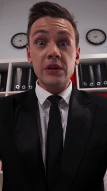 Genç Avrupalı yakışıklı iş adamı ofiste senden nefret eden bir girişimci. Kamera görüntülerinde etkileyici bir duygu var. Dikey Çekim.