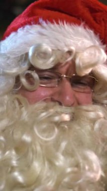 Noel Baba internetten alışveriş yaparken tablet bilgisayar kullanıyormuş. Stüdyoyu kaydırma makinesiyle yakın çekim. Gülümse, mutluluk dikey çekim.