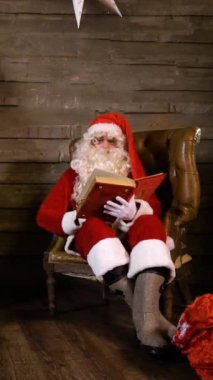 Noel Baba Kitap Oku ya da Xmas Tree yakınlarındaki fotoğraf albümü. İçinde hediyeler ve şömine olan bir çanta. Geniş aç. Noel Arifesi Dikey Vuruşu.