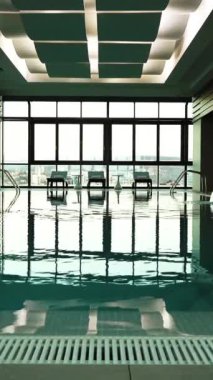 4k uhd boş mavi su temiz yüzme havuzu ya da yüksek kattaki lüks otelin kapalı su havuzu Sochi şehrinin büyük penceresinden güzel manzaralı. Dikey Çekim.