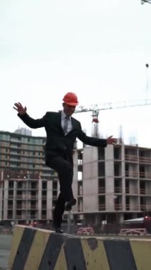 4k, UND. Takım elbiseli genç mimar ve miğfer giymiş komik maymun ve kirişin üzerinde turna ile yürüyor ve arka planda yeni inşa edilmiş bir bina var. Teal ve turuncu stil. Dikey Çekim.