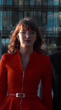 Ağır çekim. İş adamı ve iş kadını cidden anlaşmaya gidiyor. Modern iş merkezi binasında dizüstü bilgisayarla yürüyorlar. Kameranın ortasındaki haline bak. Dikey