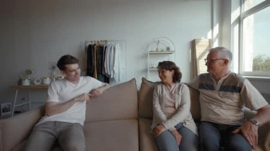 Konforlu bir oturma odasında, üç kişi çevrimiçi ve çevrimdışı ilişkilerin karmaşıklığını araştıran samimi bir tartışmaya girişiyor. İfadeleri neşe ve nostalji karışımı bir şey ifade ediyor..