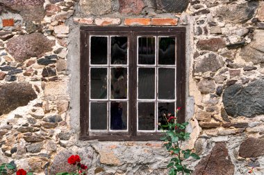 An old wooden window with glass, a fragment of an old manor