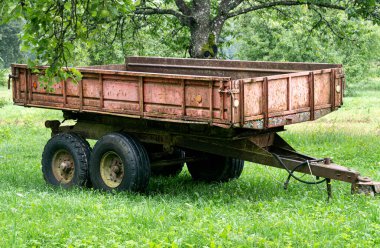 Eski paslı traktör römorku. Bir elma ağacının altında çimlerin üzerinde durmak