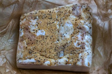 Sarımsaklı ve parşömen kağıdında baharatlı büyük bir parça domuz yağı.