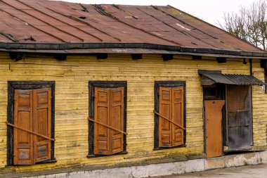 Pencereleri tahtayla kapatılmış eski ahşap bir ev.