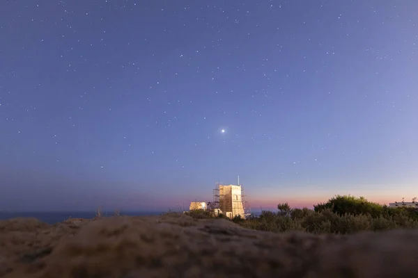 Samanyolu Malta 'nın uçurumunda zar zor parlıyor. Işık kirliliği gece gökyüzünü görmeyi zorlaştırıyor.