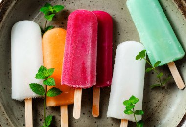group of colored ice cream on a stick on white. summer dessert