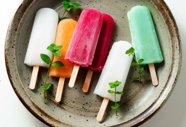 group of colored ice cream on a stick on white. summer dessert