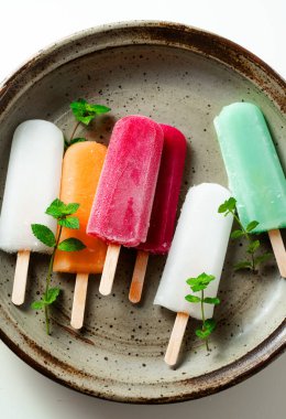 group of colored ice cream on a stick on white. summer dessert