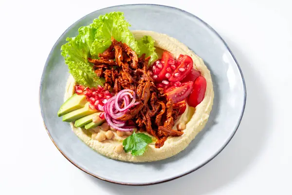 Hummus with vegan meat in barbecue sauce, tomato and avocado salad. A healthy bowl