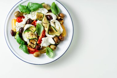 Mozzarella, zeytin, fesleğen ve ızgara sebzeli Akdeniz salatası.