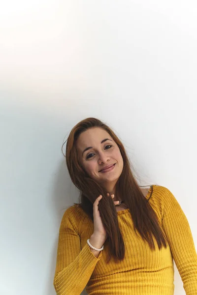 Sarı gömlekli kadın beyaz arka planda neşeli ve gülümsüyor.