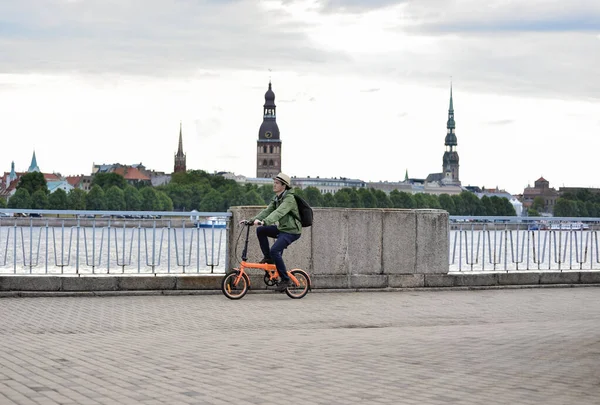 Bir adam bisikletiyle Daugava Nehri 'nin arka planına ve Letonya' nın eski Riga kasabasına doğru gidiyor. Bisiklet turu sırasında turist.