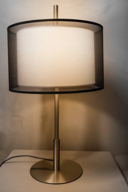 Yatak odasındaki komodinin üzerinde gece lambası, rahat bir atmosfer için iç aydınlatma elementi.