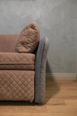 Modern bej bir kanepenin parçası oturma odasındaki gri duvara yaslanmış.