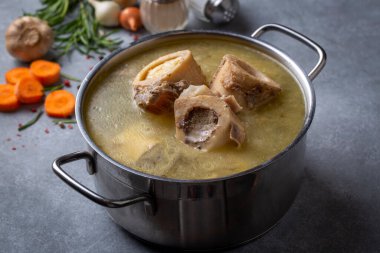 Boiled bone and broth. Homemade beef bone broth is cooked in a pot on. Bones contain collagen, which provides the body with amino acids, which are the building blocks of proteins. clipart